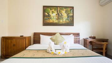 Uma cama bem arrumada com travesseiro decorativo, cabeceira de madeira, mesa de cabeceira de madeira, uma pequena mesa e uma cadeira.