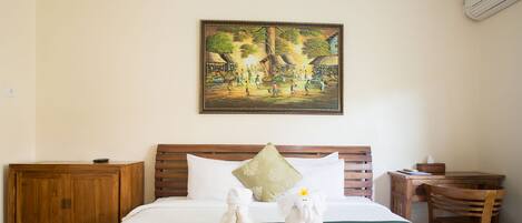 A neatly made bed with a decorative pillow, a wooden headboard, a wooden nightstand, a small table, and a chair.