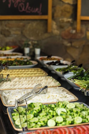A buffet with various food items including sliced cucumbers, cheese, and vegetables. - Armagrandi Bozcaada (Bozcaada)