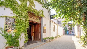 A narrow cobblestone street with a building on the left featuring a wooden door and a signboard. - Armagrandi Bozcaada (Bozcaada)