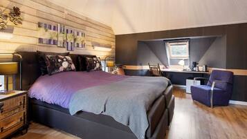 A bedroom with a large bed, a desk, and a chair.