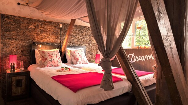 A bedroom with a stone wall, a bed with a canopy, and a 'Dream' sign on the window. - Bij Aquamarijn (Stieltjeskanaal)