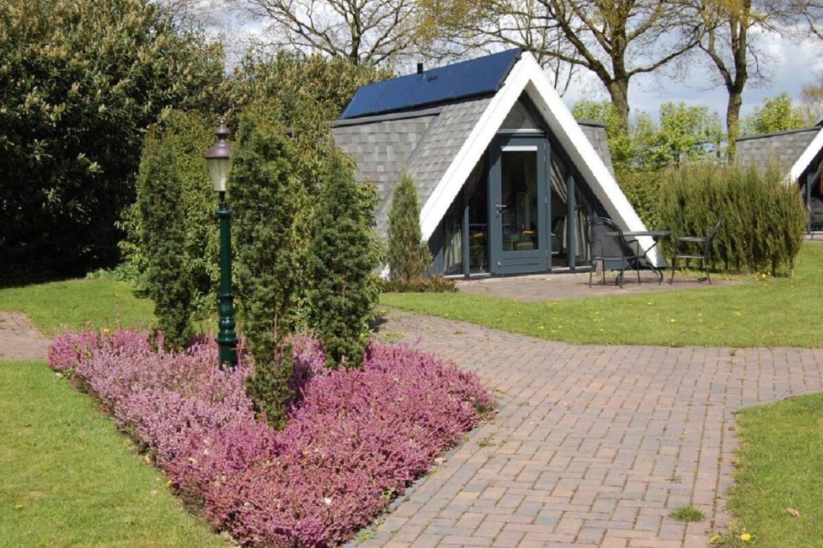 Un bâtiment doté d’un toit triangulaire et d’un chemin pavé menant à l’entrée.