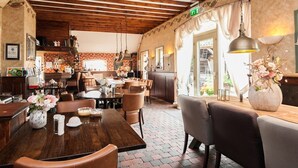 A restaurant with wooden ceiling beams, a bar area, and a dining area with tables and chairs. - Bij Aquamarijn (Stieltjeskanaal)