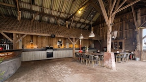 A rustic interior with a brick floor, wooden beams, a bar area, and a dining space with tables and chairs. - Bij Aquamarijn (Stieltjeskanaal)