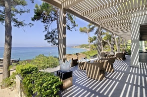 A covered outdoor seating area with wicker furniture and a view of the sea. - White Rocks Hotel Kefalonia (Kefalonia)