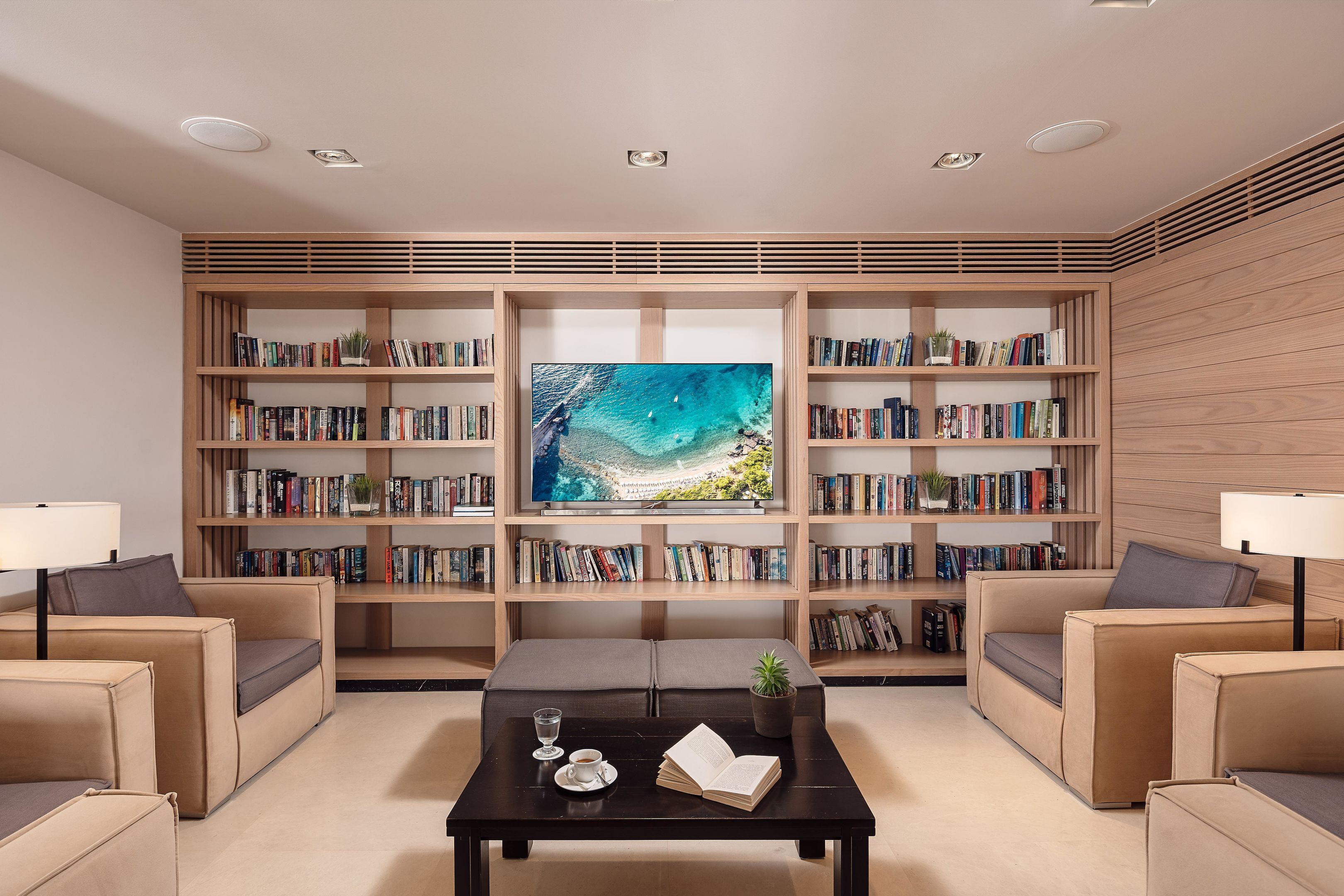 A modern living room with a large bookshelf, a flat-screen TV, and comfortable seating.