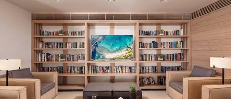 A modern living room with a large bookshelf, a flat-screen TV, and comfortable seating.