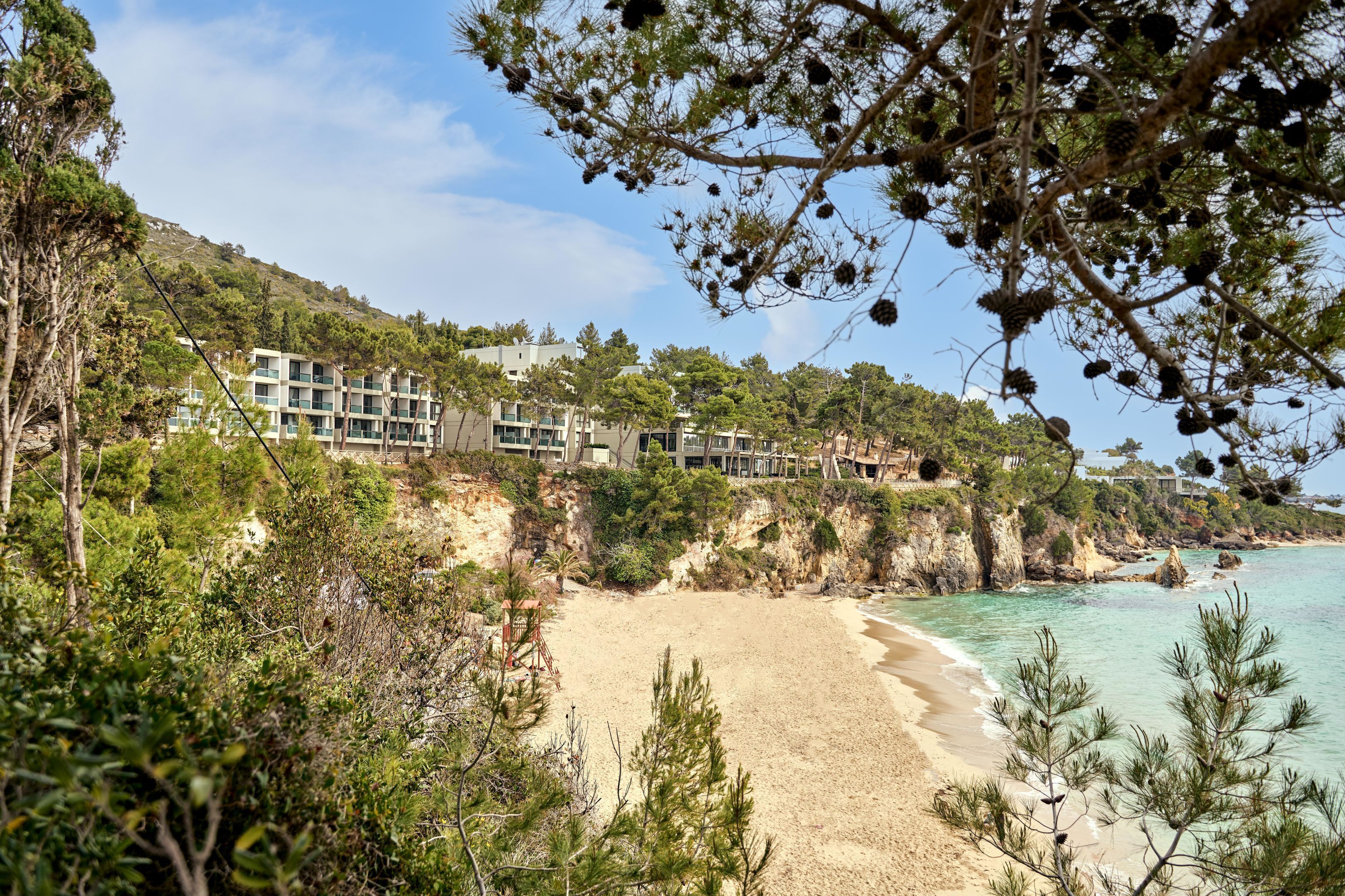 Ein Küstenhotel mit mehreren Gebäuden, einem Sandstrand und freiem Blick auf das Meer.