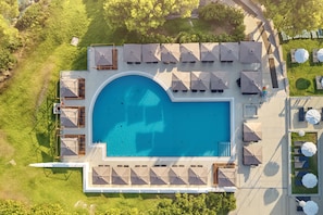 Alberca al aire libre, sombrillas en la alberca y camastros