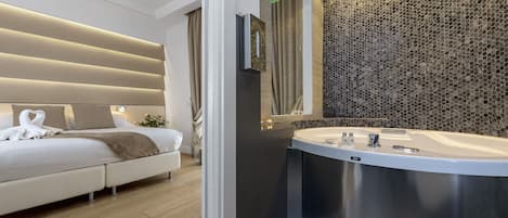 A modern bedroom with a large bed, a built-in vanity with a bathtub, and a textured wall.