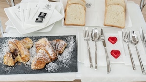 A breakfast setup with bread, pastries, and cutlery on a tray. - Vatican Style (Rome)