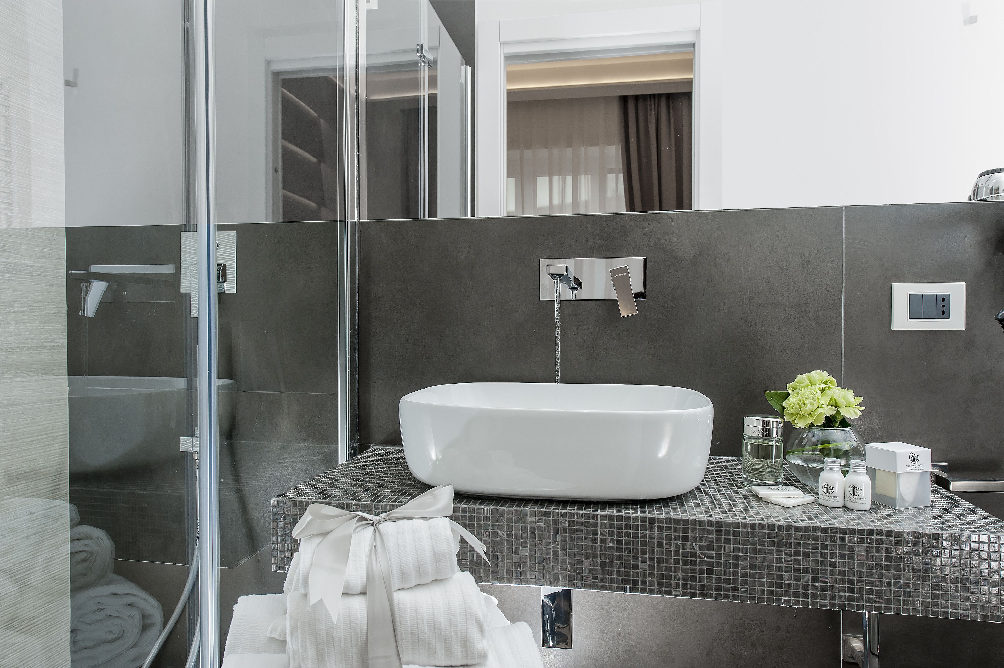 A modern bathroom with a large white bathtub, a glass shower enclosure, and a tiled floor.