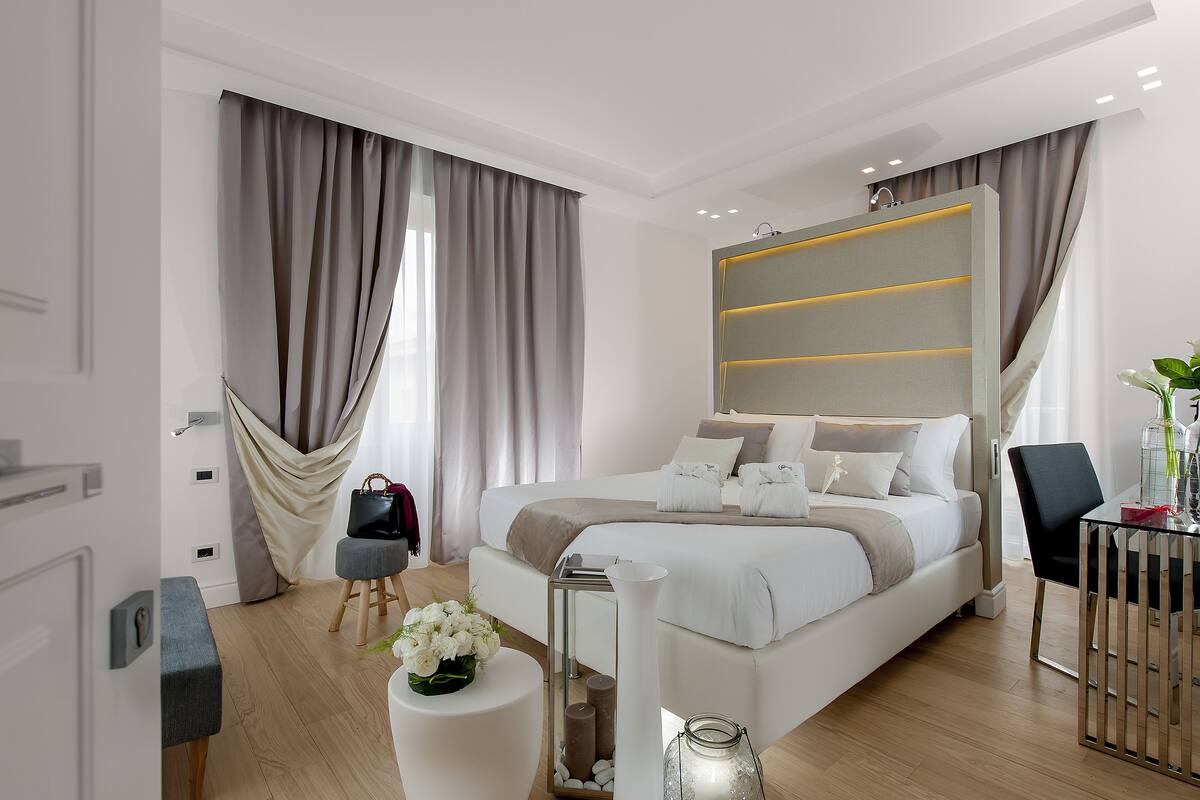 A modern bedroom with a large bed, a bedside table, a chair, and a desk.