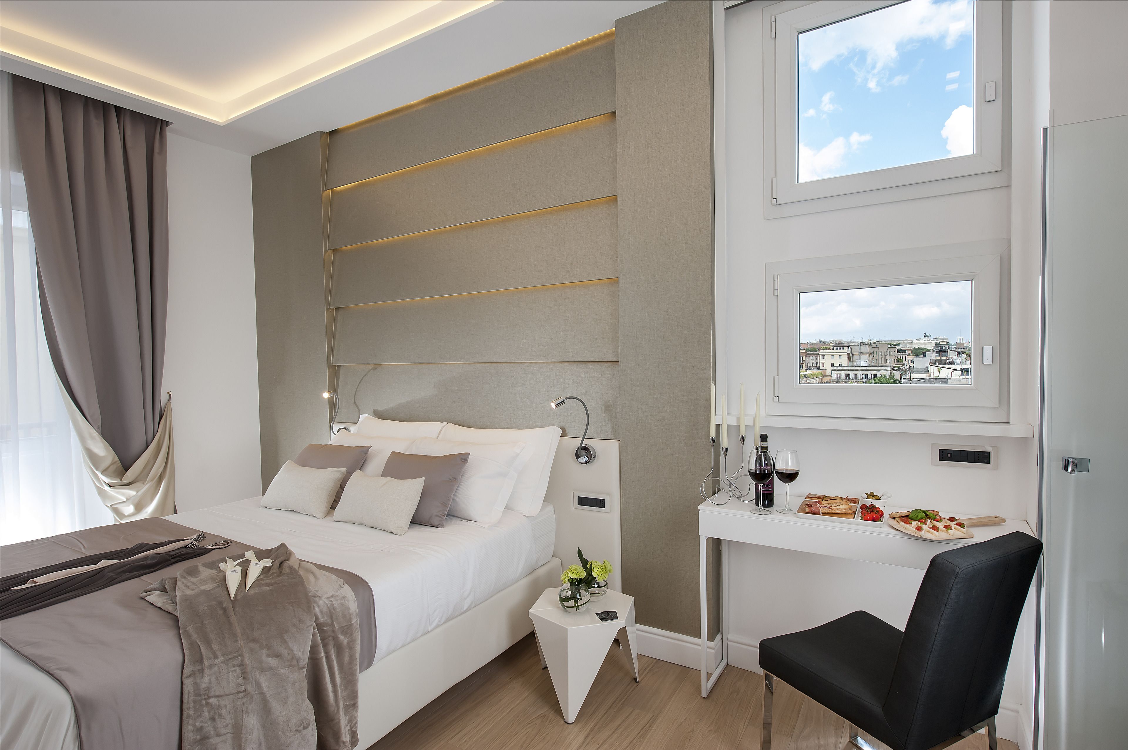 Una moderna camera d'albergo con un letto, un comodino e una scrivania con vista sulla città.
