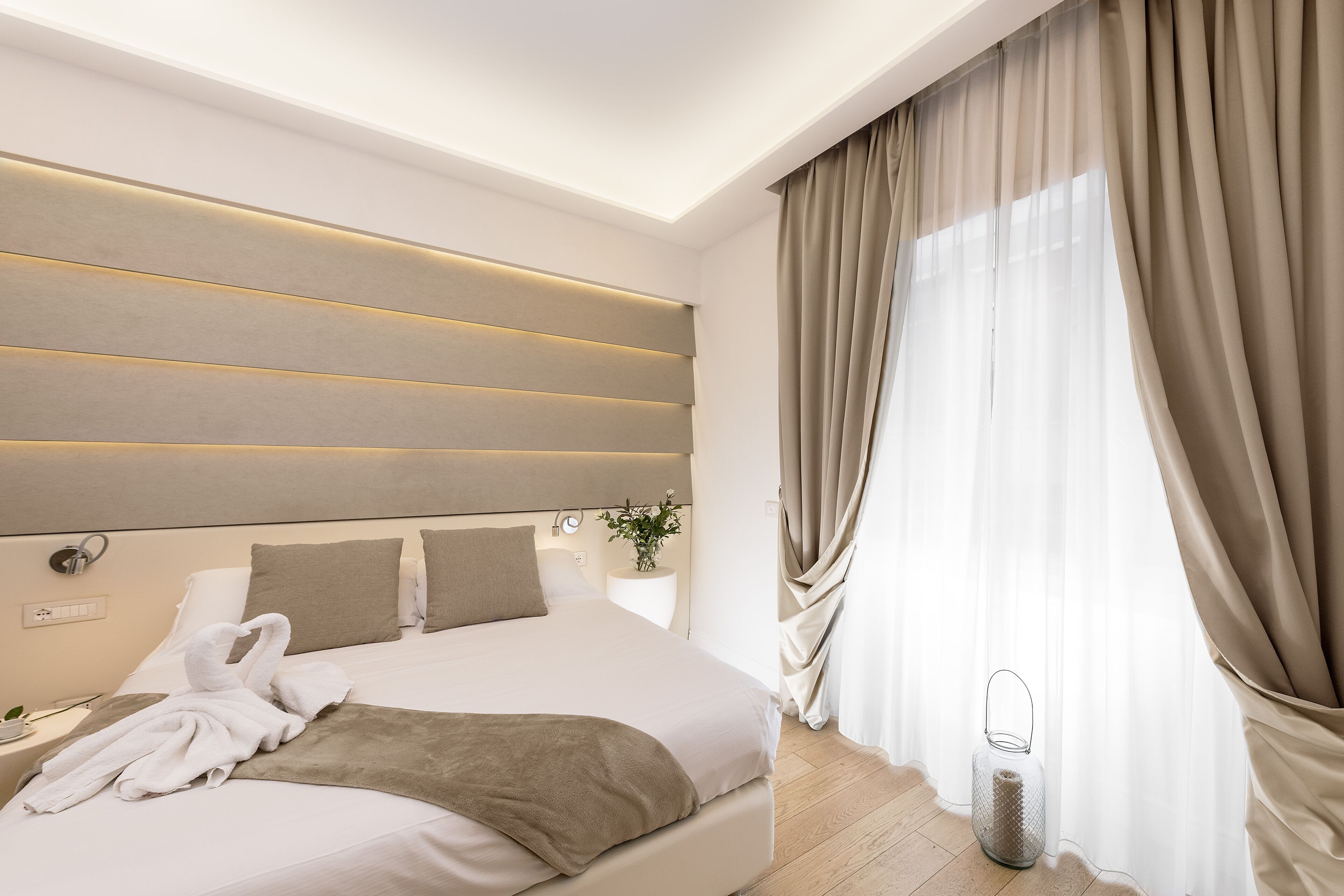 A modern hotel room with a large bed, a bedside table, a nightstand, and a lamp.