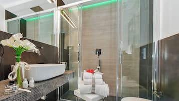 A modern bathroom with a large white sink, a glass shower enclosure, and a white toilet.