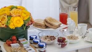 A breakfast table with sandwiches, fruit, cereal, and juice.
