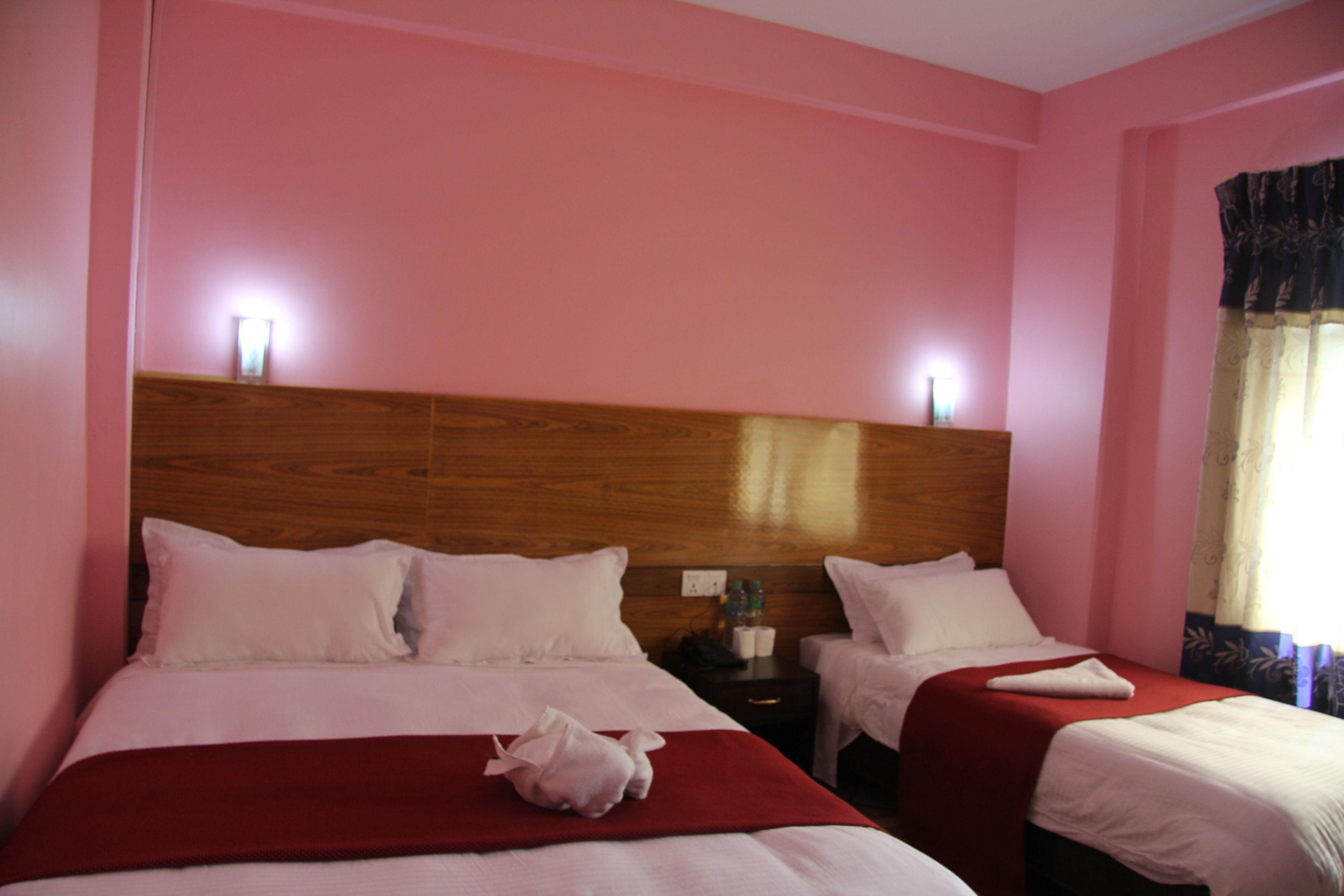 A hotel room with two beds, wooden headboard, white bedding, and a red blanket.