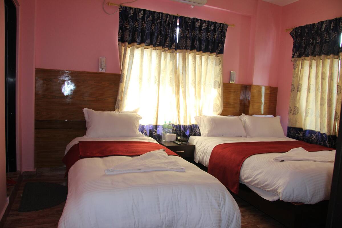 A hotel room with two beds, wooden headboards, and pink walls.