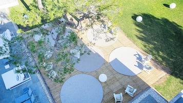 An aerial view of a patio area with a wooden deck, seating arrangements, and a central tree.