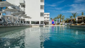 Una piscina al aire libre, sombrillas, sillones reclinables de piscina