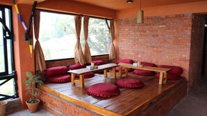 A cozy room with a brick wall, wooden bench seating, and red cushions. - Nar-Bis Hotel (Pokhara)