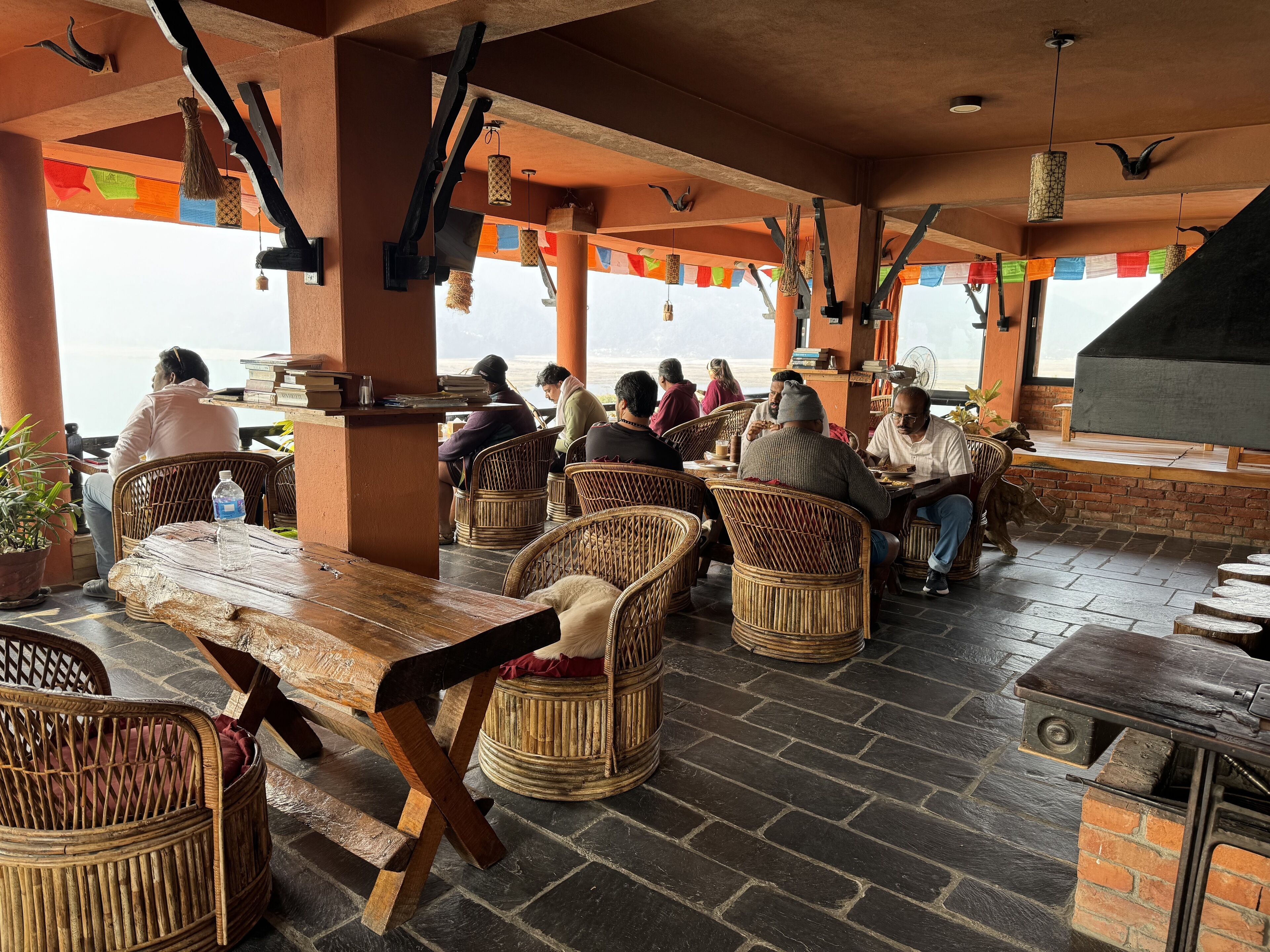A restaurant with wicker furniture, a brick fireplace, and a view of the sea.