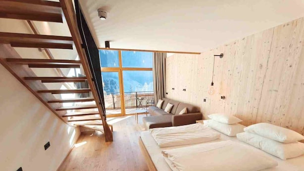 Un dormitorio moderno con una cama grande, un sofá, una escalera y un balcón con vistas.