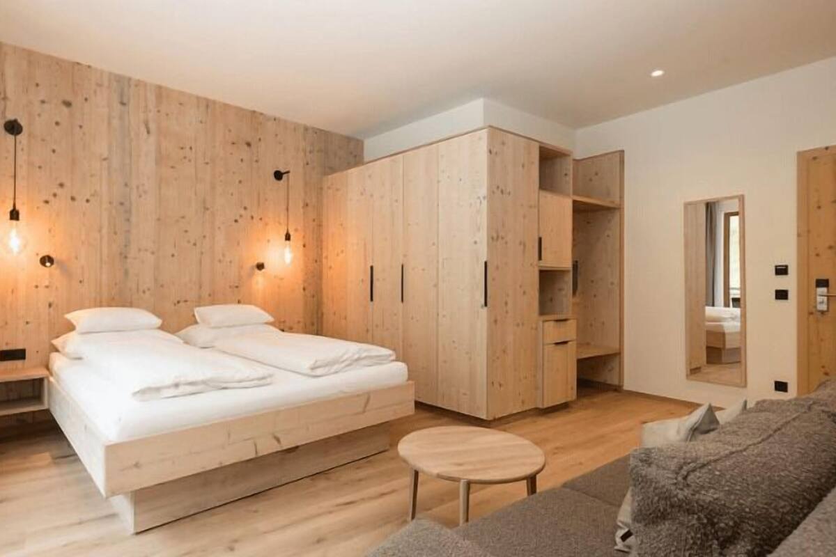 Un dormitorio moderno con pared de madera, cama, armario y sofá.