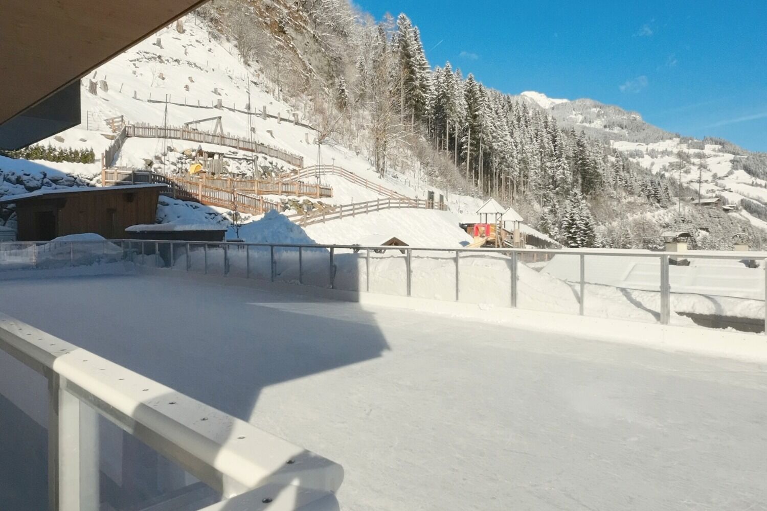 Pista de esquí cubierta de nieve con estructuras de madera y cielo despejado.