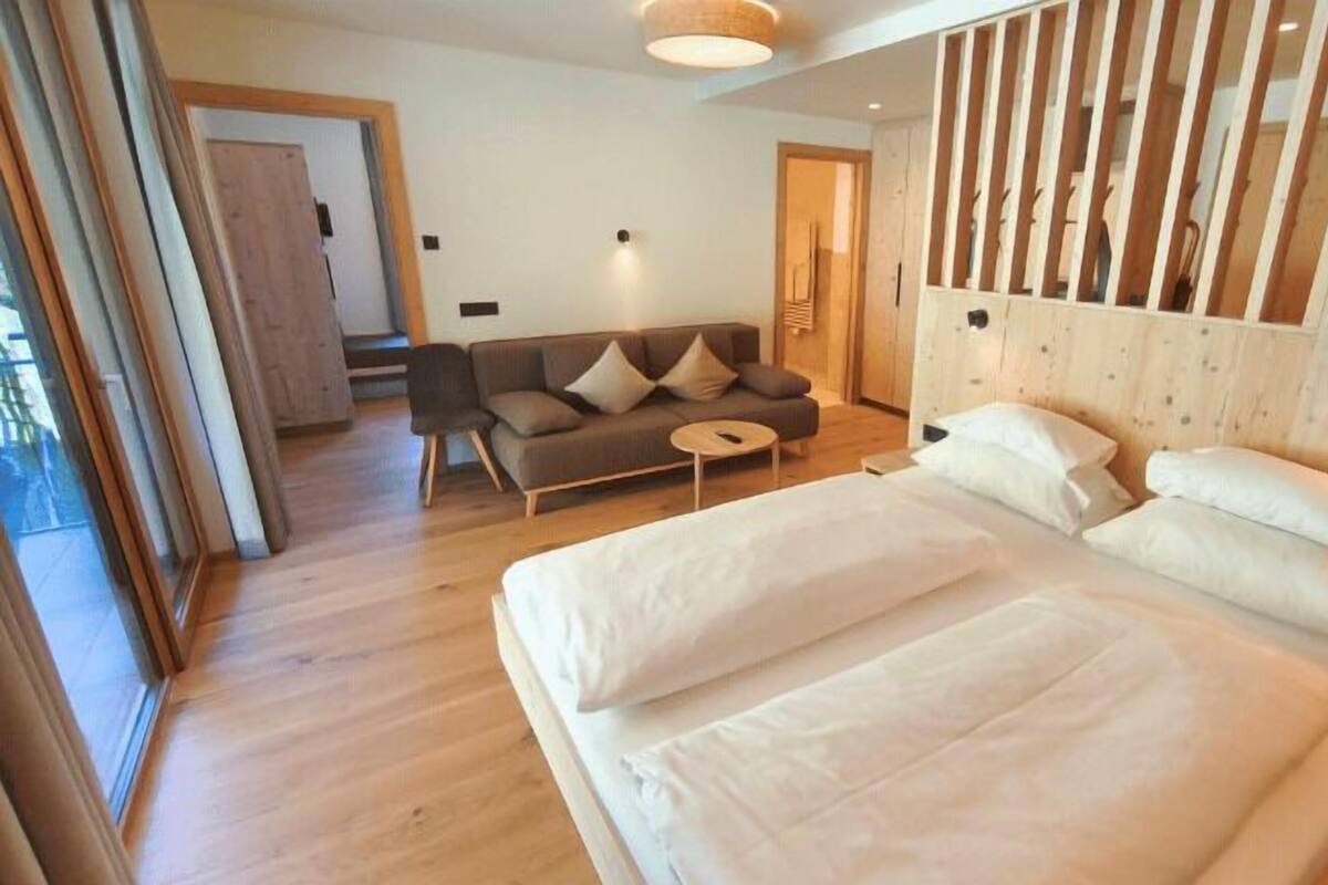 Una habitación de hotel moderna con una cama grande, un sofá y una mesita.