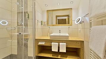A modern bathroom with a glass-enclosed shower, a wooden vanity with a sink, and a mirror above the vanity.
