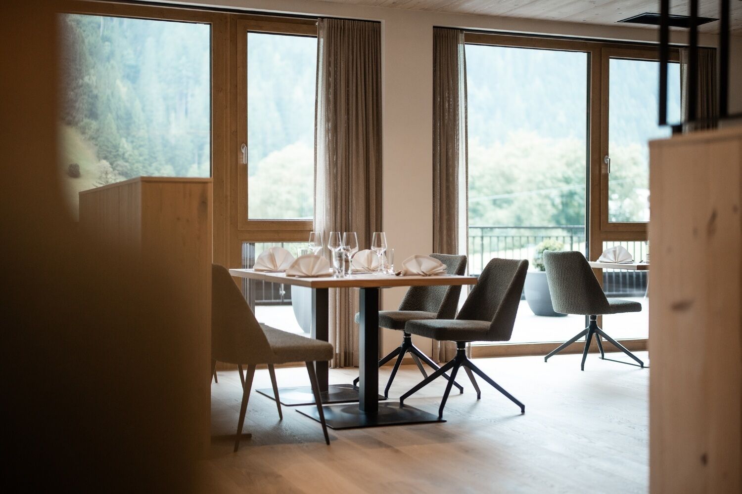 A dining area with a table set for four, large windows, and a view of the outdoors.