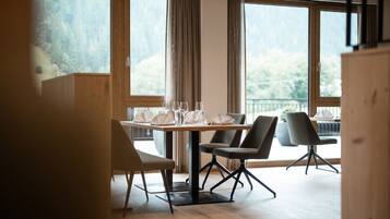 A dining area with a table set for four, large windows, and a view of the outdoors.