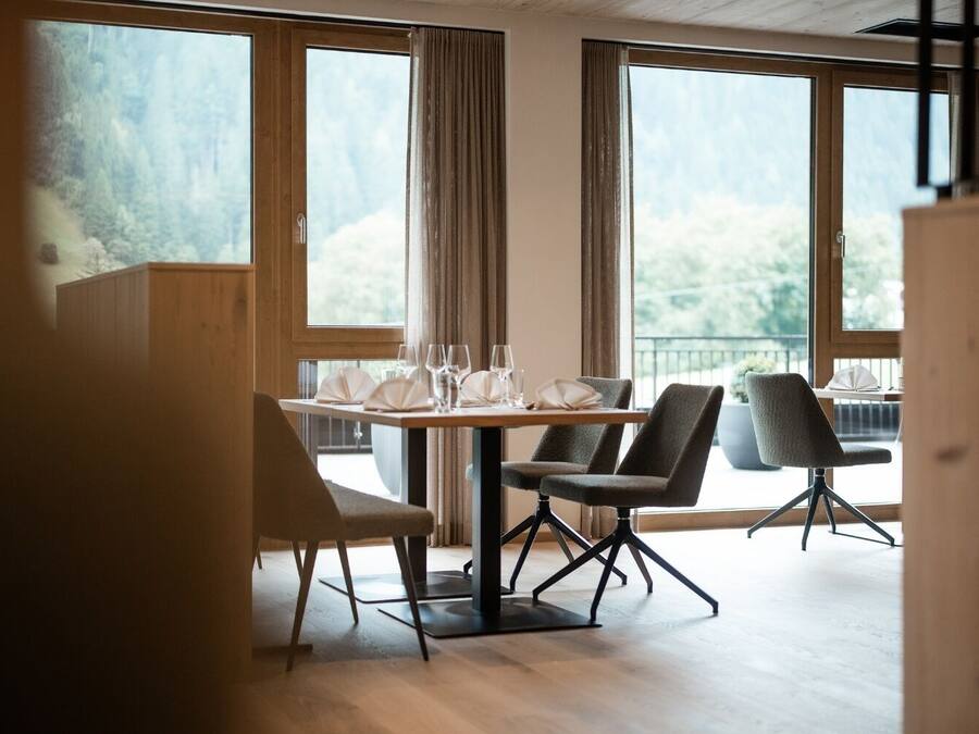A dining area with a table set for four, large windows, and a view of the outdoors.