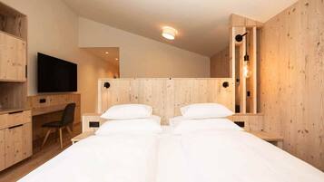 Un dormitorio moderno con dos camas, paredes de madera, un escritorio y un televisor.
