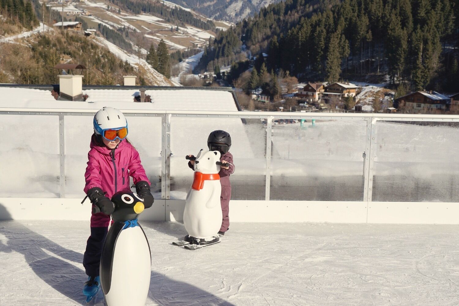 Dos niños en una pendiente nevada con vistas a la montaña.