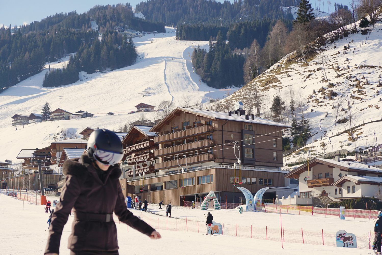 A ski resort with wooden buildings, ski slopes, and a ski lift.