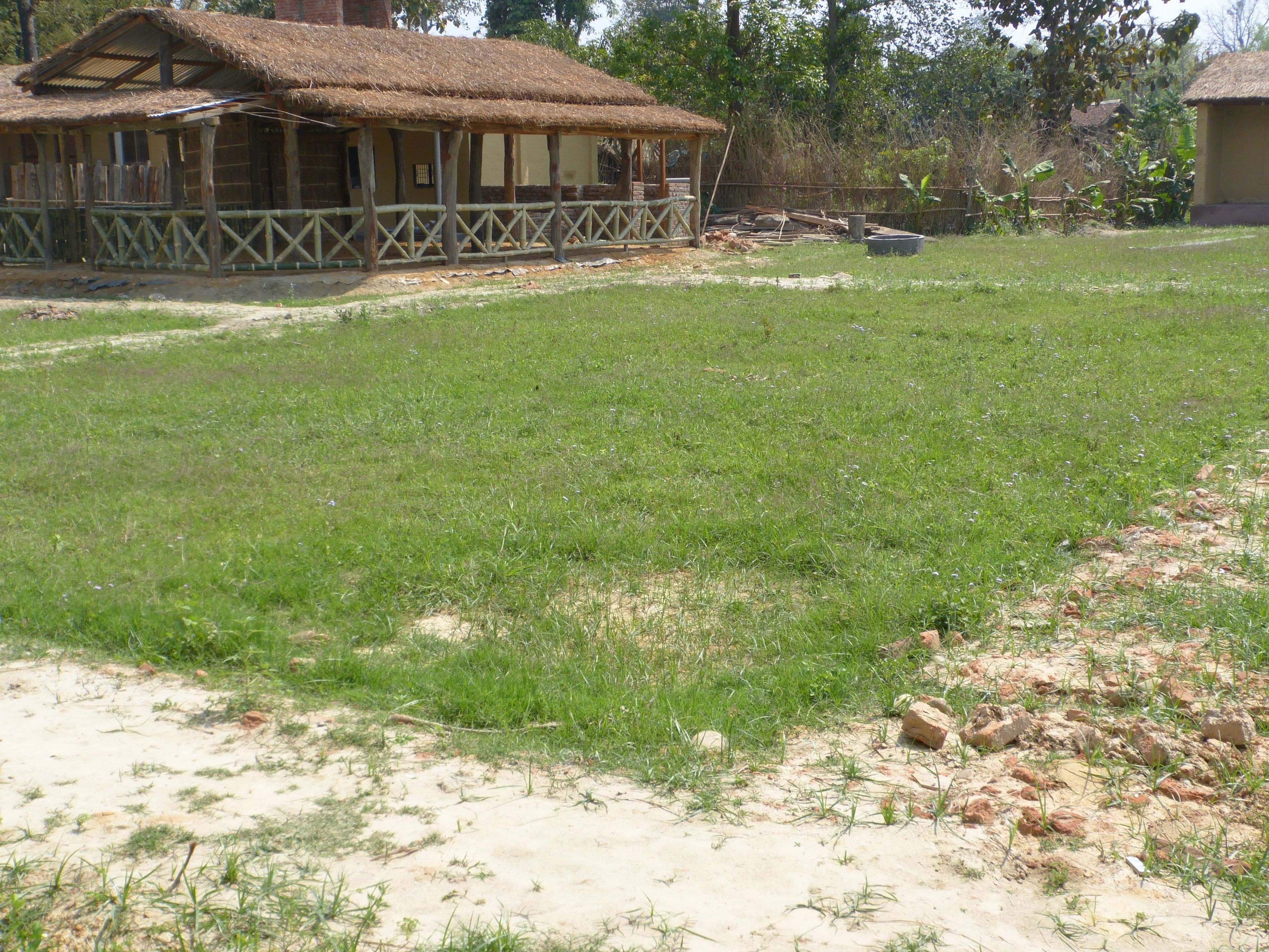 Una casa rústica con techo de paja y un patio cercado.