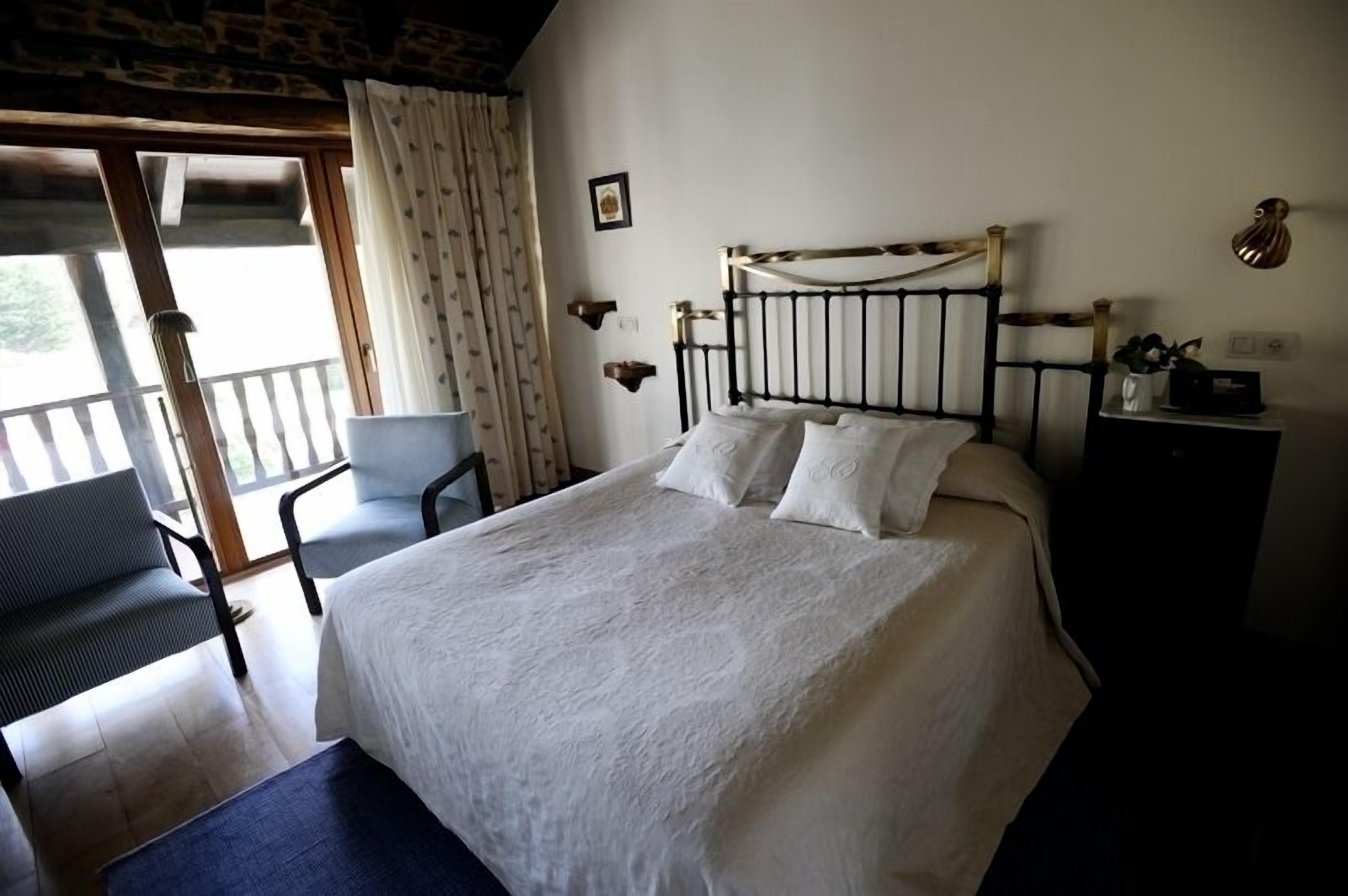Une chambre à coucher avec un lit, une chaise, un bureau et un balcon.