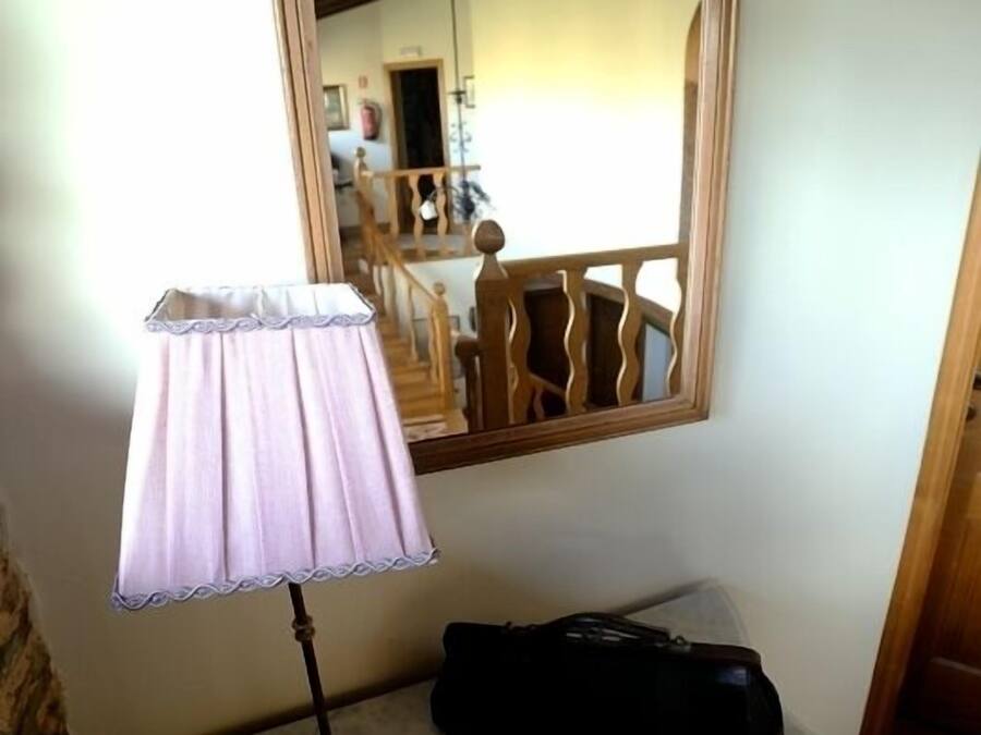 Une pièce avec un miroir à cadre en bois, une table blanche avec une lampe et un sac noir.