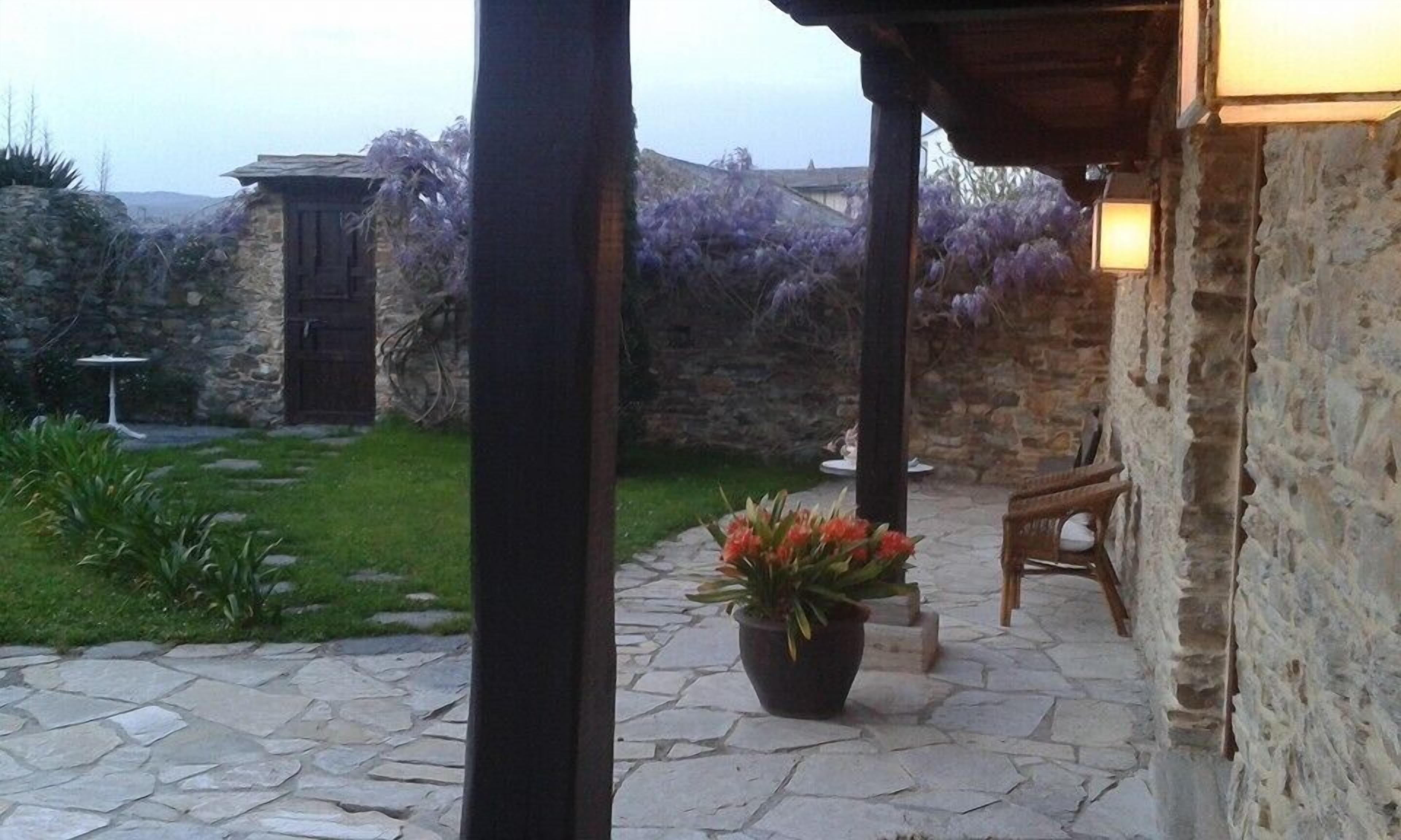 A stone patio with a potted plant, a wooden bench, and a stone wall.