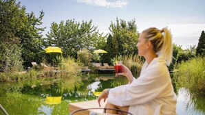 Une femme est assise sur un quai, au bord d’un lac paisible, avec des parasols jaunes en arrière-plan.