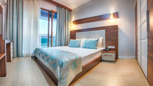 A modern hotel room with a large bed, wooden headboard, and a view of the sea through floor-to-ceiling windows. - The Green Park Termal Sivas Hotels &Spa (Yildizeli)