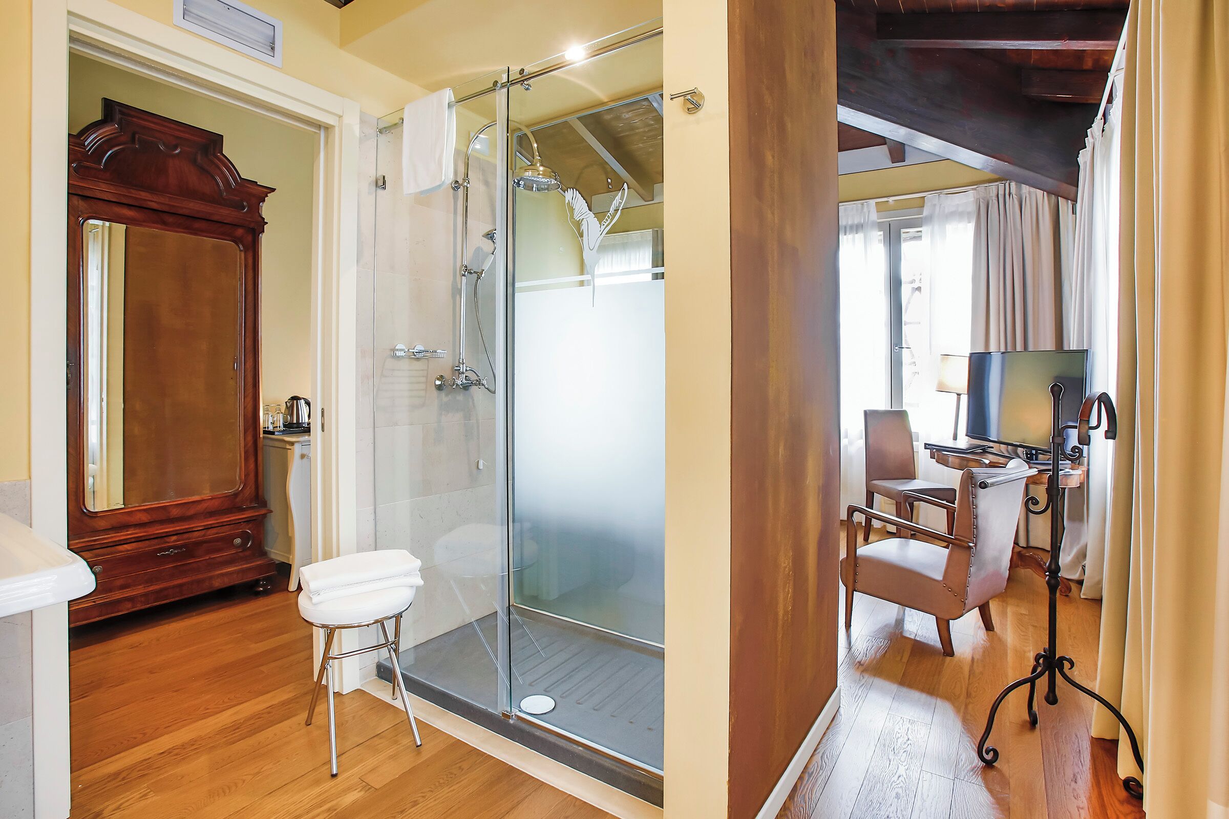 Un baño con cabina de ducha de vidrio, tocador de madera y retrete blanco.