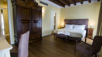 Une chambre à coucher avec une grande armoire en bois, un lit avec du linge de lit blanc et deux tables de chevet avec des lampes.