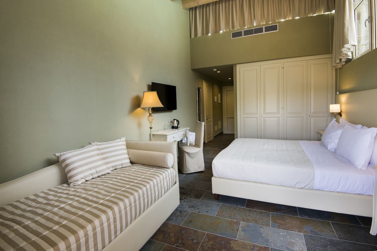 Una habitación de hotel con dos camas, una mesita de noche, una lámpara y un televisor.