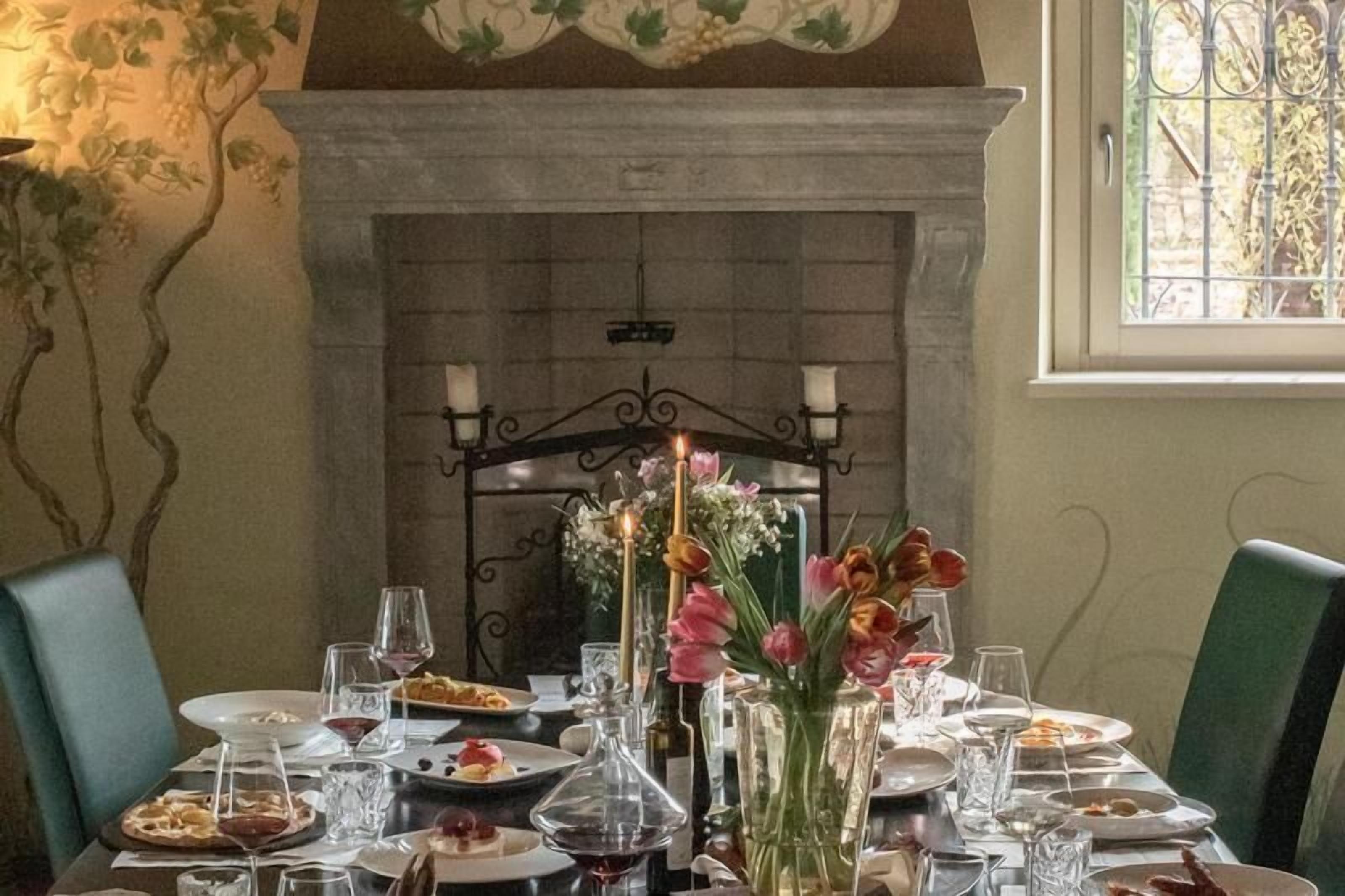 A dining table set for a meal with candles, flowers, and wine glasses.