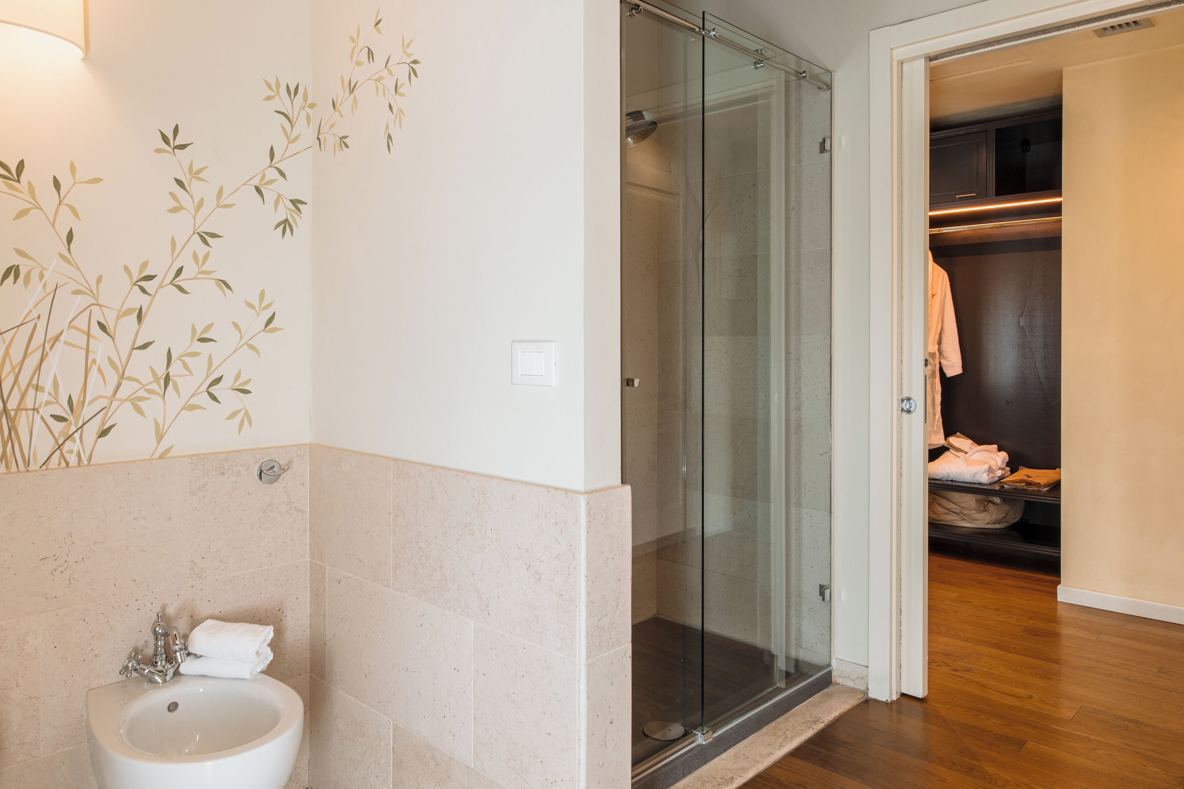 Een badkamer met een glazen douche, een wastafel en een handdoekrek.